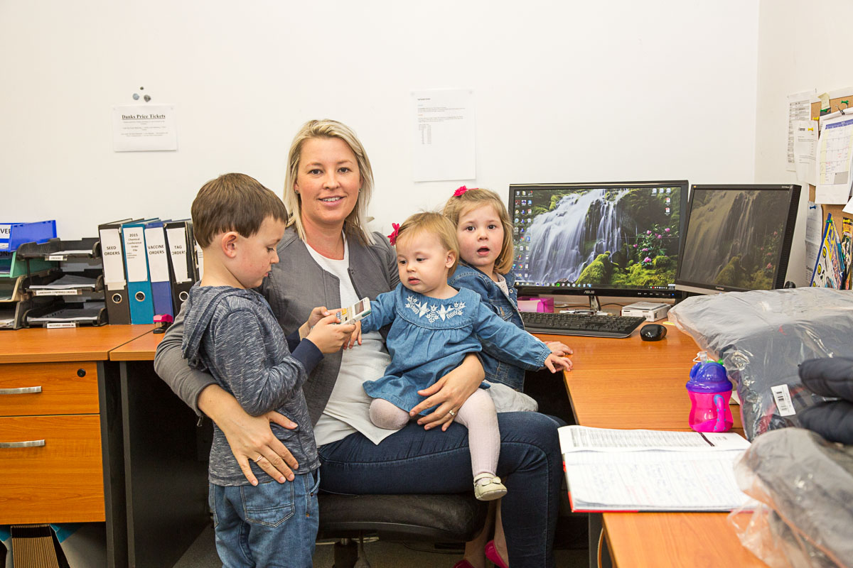 Photo of mother at office desk surrounded by her three young children. Photo by caro telfer, photographer.