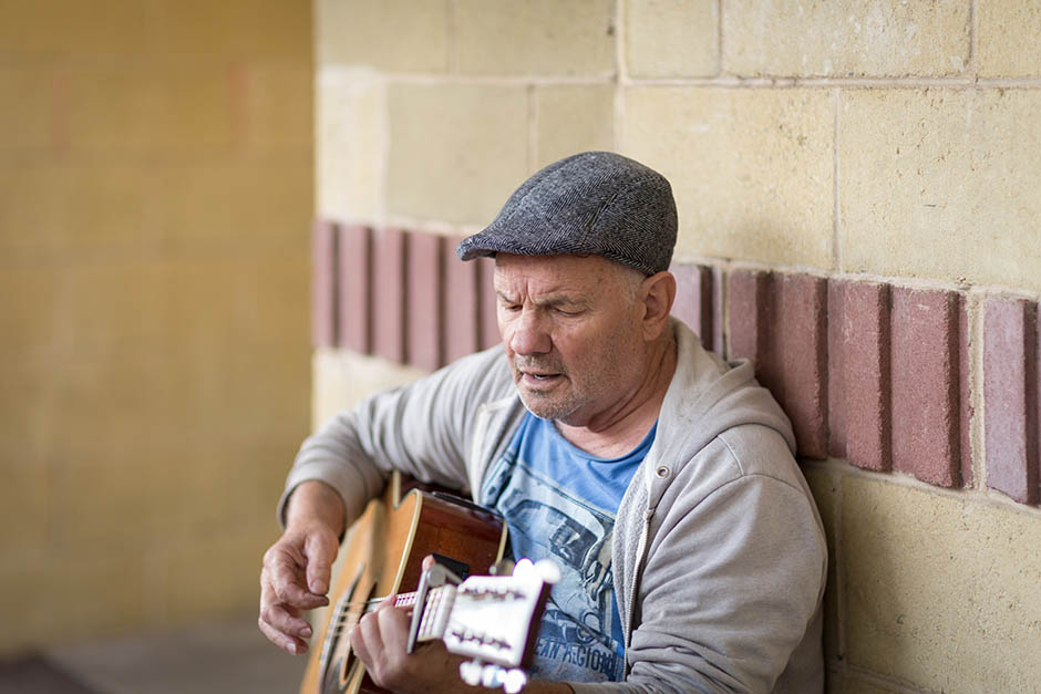 photo of a man playing a guitar, by caro telfer, photographer