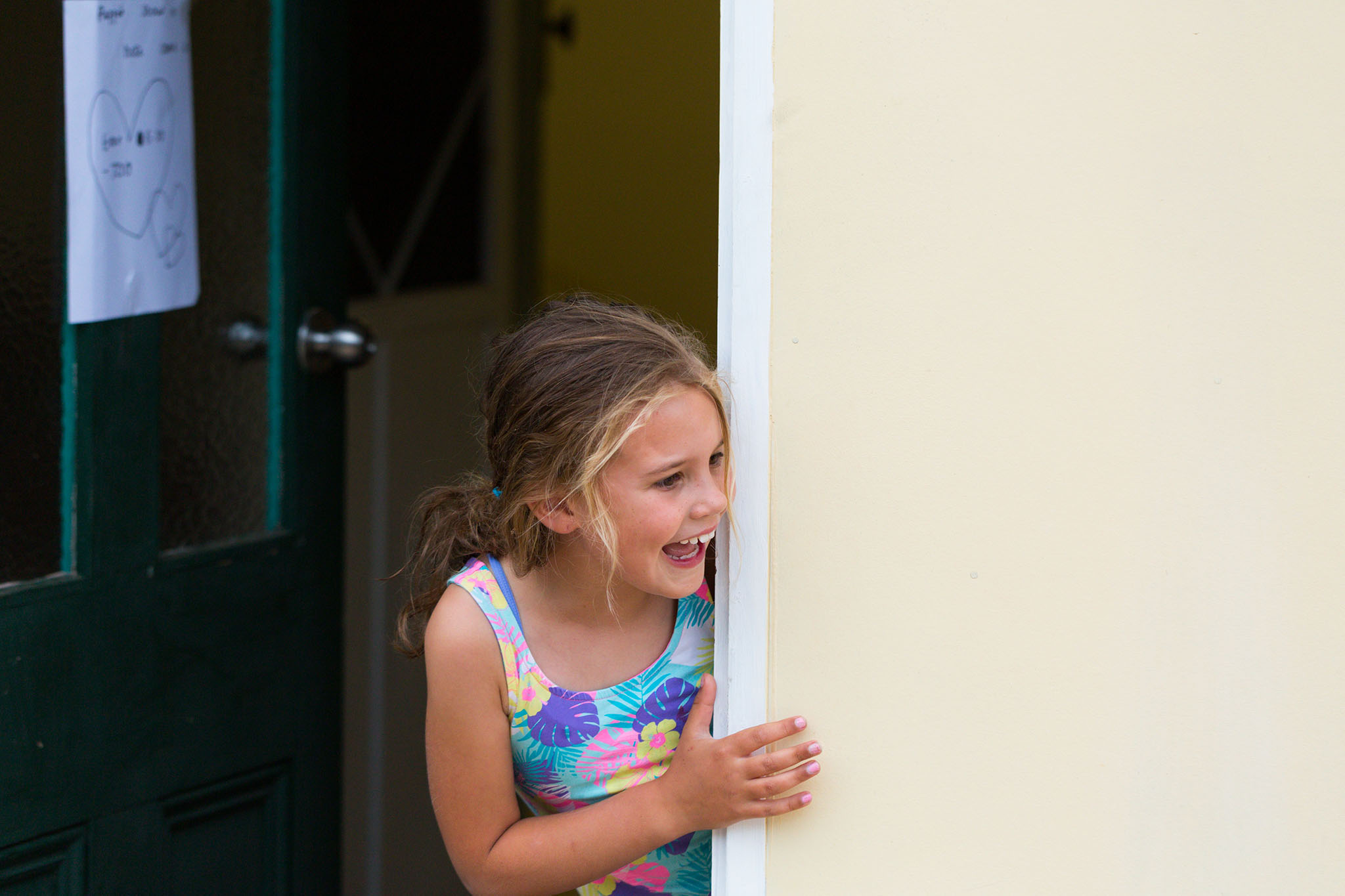 Photo of a child peeking around the doorway. Photo by Caro Telfer, photographer.